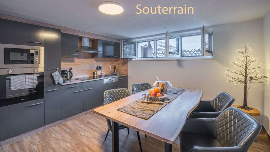 Küche mit Esstisch im Appartement Top 1 mit geöffneten Fenstern